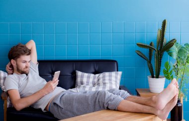 Mutlu adam bir c oturan bir akıllı telefon medya içeriği izlerken