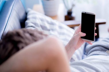 Mutlu adam bir kanepede oturan bir telefonda medya içeriği izlerken bir