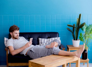 Mutlu adam bir c oturan bir akıllı telefon medya içeriği izlerken