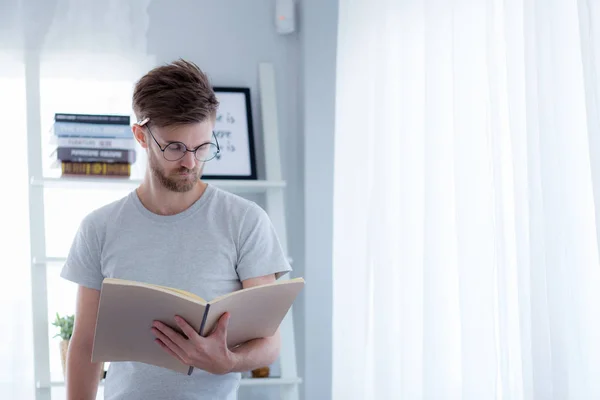 Bello ragazzo in occhiali sta leggendo libro preparazione esame con s — Foto Stock
