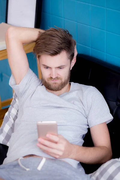 Felice uomo guardando contenuti multimediali in uno smartphone seduto su un c — Foto Stock