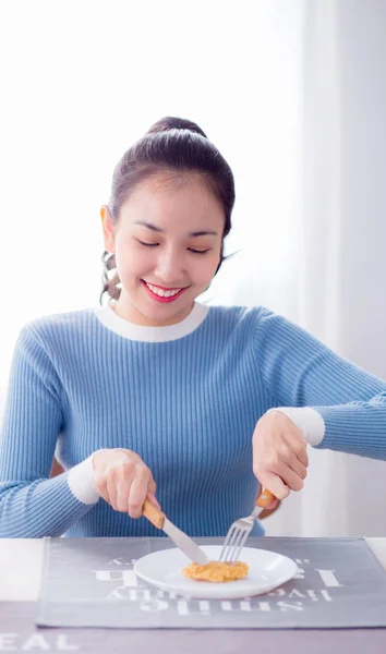 Pretty hona hålla sked och kniv äta mat i köket. — Stockfoto