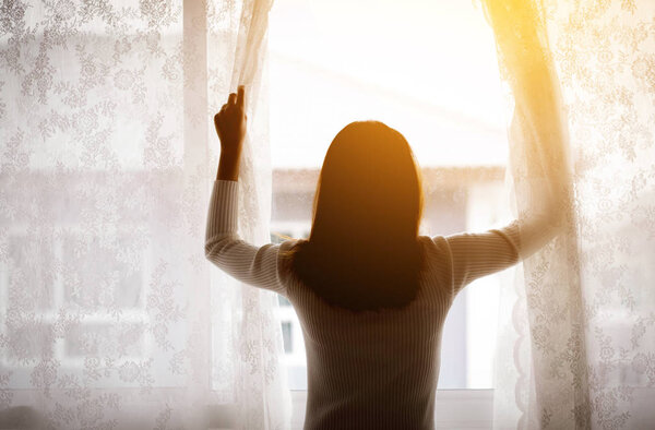 woman and hope concept - woman opening window curtains business 