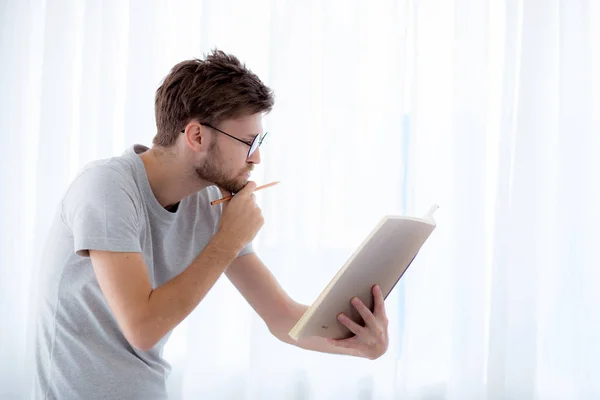 Bonito cara em óculos está lendo livro preparando exame e th — Fotografia de Stock