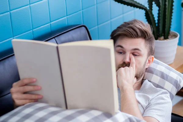 Relax uomo leggendo un libro sdraiato sul divano concetto di educazione . — Foto Stock