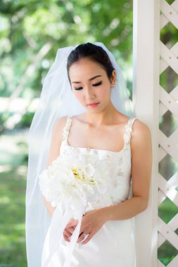yeşil bir bahçede duran ve bir weddin tutan bir elbise gelin