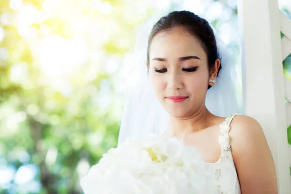 Novia en un vestido de pie en un jardín verde y la celebración de una boda —  Fotos de Stock