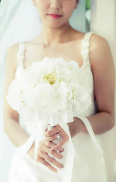 Noiva em um vestido de pé em um jardim verde e segurando um casamento — Fotografia de Stock