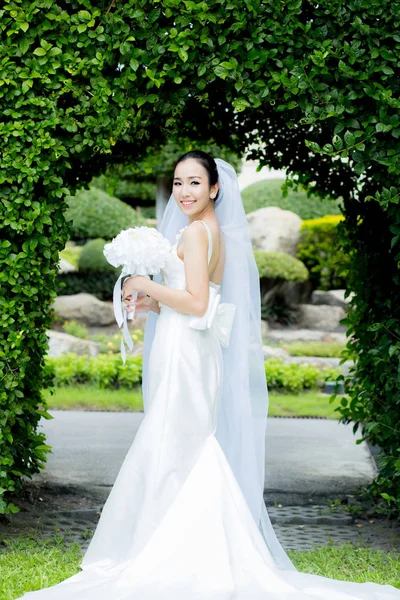 Beautiful young woman on wedding day in white dress in the garde — Stock Photo, Image