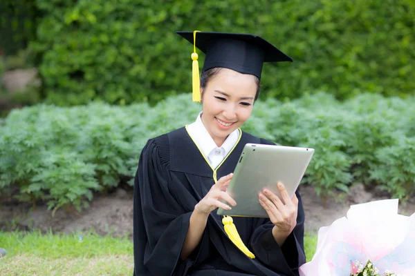 Graduate playing tablet in her hand feeling relaxing and so happ