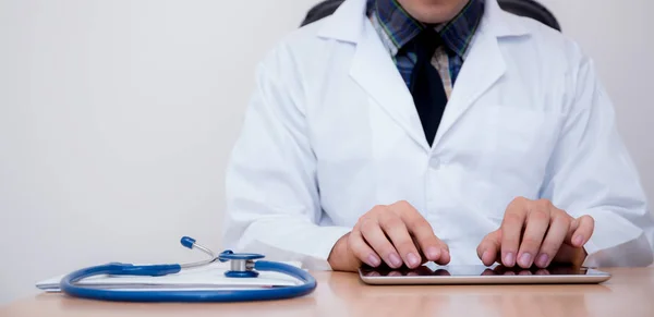 Male doctor with tablet computer and stethoscope at the desk on — Stock Photo, Image