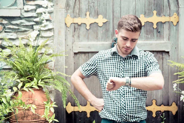 Hombre de pie en el jardín mirando el reloj de mano - El tiempo es dinero . —  Fotos de Stock