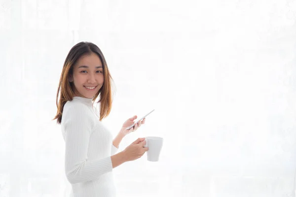 Schöne junge Frau im weißen Pullover, die Kaffee und Holdi trinkt — Stockfoto