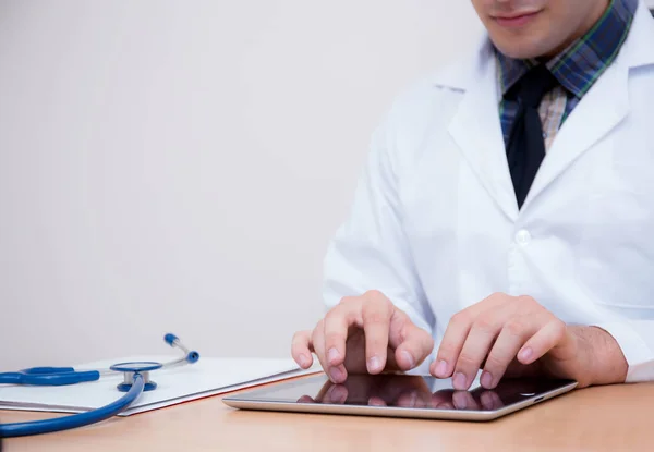 机の上にタブレットコンピュータと聴診器を持つ男性医師 — ストック写真