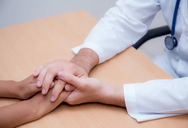 Vriendelijke mannelijke arts hand houden patiënt hand zittend op de de — Stockfoto