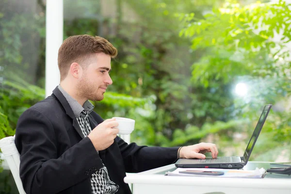 Heureux jeune homme tenant une tasse de café et souriant dans le salon — Photo