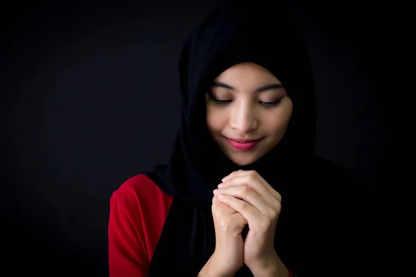 Religious young Muslim woman praying over black background. — Stock Photo, Image