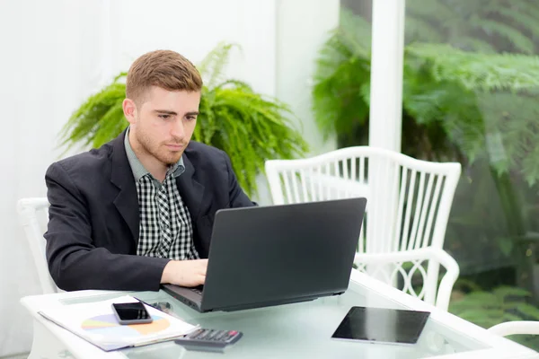 Homem de negócios e sorrindo, como ele trabalha em seu laptop na vida — Fotografia de Stock