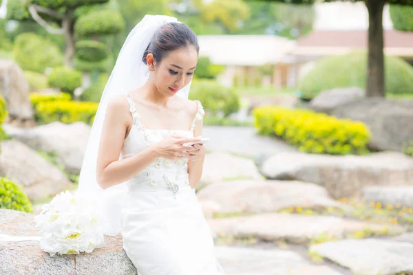 Toque de noiva no telefone no vestido de noiva no jardim . — Fotografia de Stock
