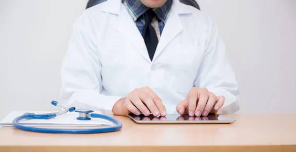 Мужчина врач с планшетным компьютером и стетоскопом за столом на — стоковое фото
