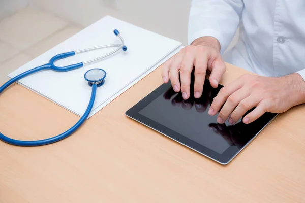 Médico masculino com computador tablet e estetoscópio na mesa em — Fotografia de Stock