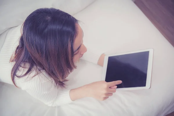 Kobieta leżąca w sypialni z cyfrowym tabletem dotykając palcem — Zdjęcie stockowe