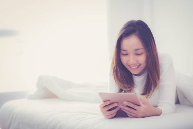 parmakla dokunan dijital tablet ile yatak odasında yatan kadın 