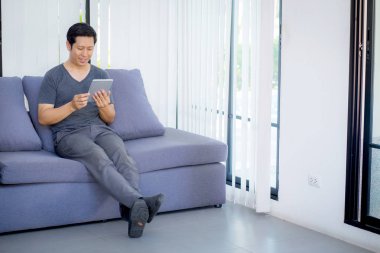 kanepede oturan bir tablet medya içeriği izlerken işadamı