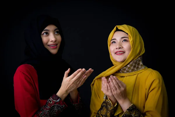 Religious young Muslim two women praying over black background. — Stock Photo, Image