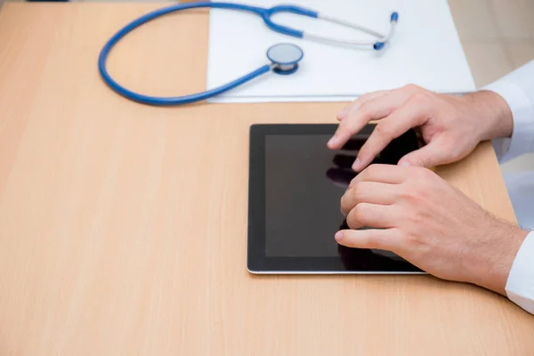 Male doctor with tablet computer and stethoscope at the desk on — Stock Photo, Image