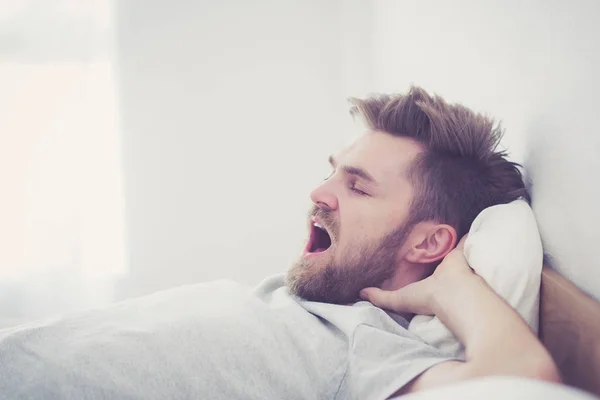 Όμορφος νέος Αμερικανός αρσενικό χασμουριέται κοιμούνται στο κρεβάτι στο σπίτι-επουλώνεται — Φωτογραφία Αρχείου