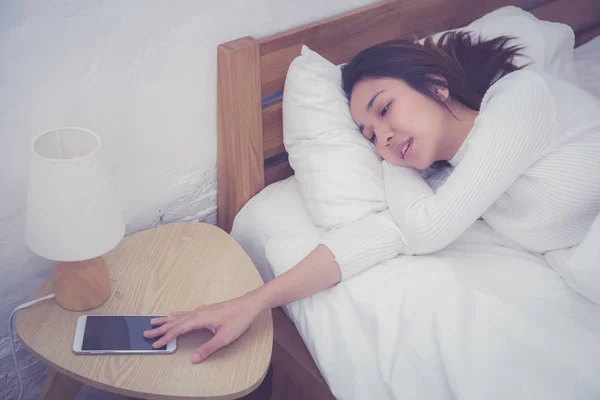 Ręka senny kobieta budząc się z budzikiem na telefon komórkowy — Zdjęcie stockowe