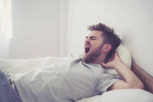 Красивый молодой американец зевает, спит в постели дома - исцелить — стоковое фото