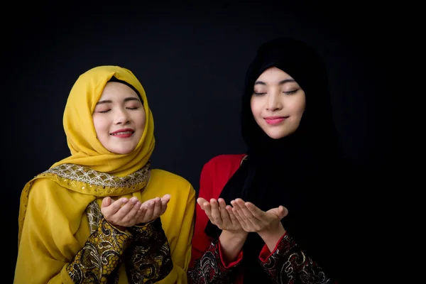 Religiosa joven musulmana dos mujeres rezando sobre fondo negro . — Foto de Stock