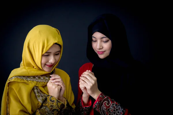 Religiosa joven musulmana dos mujeres rezando sobre fondo negro . — Foto de Stock