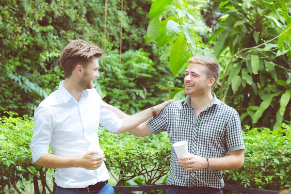 Dos amigos hombres hablando de pie en un jardín . —  Fotos de Stock