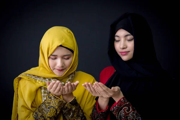 Religious young Muslim two women praying over black background. — Stock Photo, Image