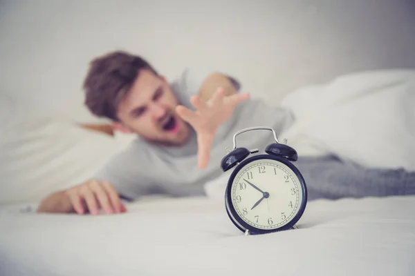 Man sleepy nationality american reaching for the alarm clock sle — Stock Photo, Image
