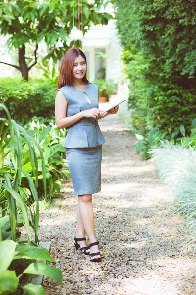 business woman in the garden looking tablet - happy and smiling.
