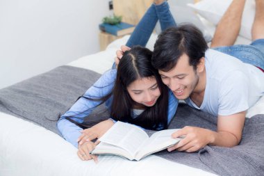 Çift ha ile sabah yatak odasında birlikte bir kitap okuma