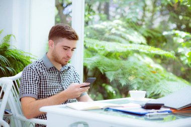 Akıllı telefon kullanan ve gülümseyen kendine güvenen yakışıklı genç adam