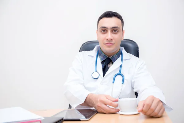 Pewny mężczyzna lekarz siedzi na biurku i odpocząć, medyczne — Zdjęcie stockowe