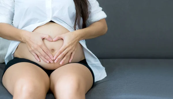 Embarazada asiática mujer celebración gesto corazón símbolo forma vientre wi —  Fotos de Stock