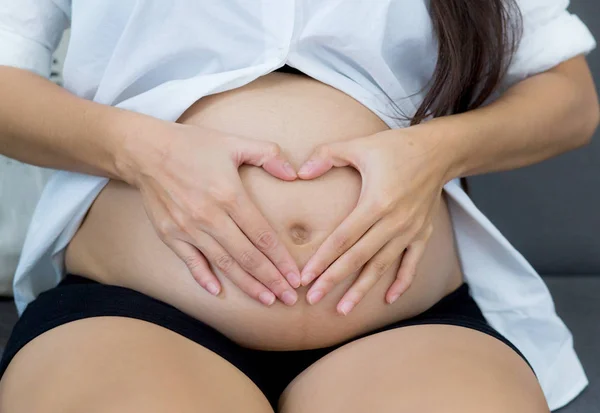 Embarazada asiática mujer celebración gesto corazón símbolo forma vientre wi —  Fotos de Stock