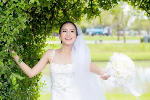 Красива молода жінка в день весілля в білій сукні на дереві — стокове фото