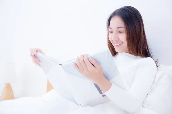 Mujer asiática leyendo un libro y sonriendo en el dormitorio. estilo de vida con —  Fotos de Stock