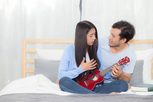 Unga asiatiska paret spelar ukulele avkopplande med lycka och j — Stockfoto