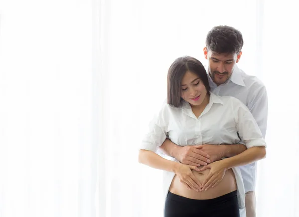 Gravid mor och far stående kramas håller magen hjärta — Stockfoto