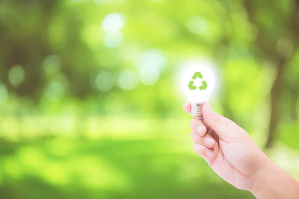 Man hand vasthouden gloeiende gloeilamp met recycle symbool op Natur — Stockfoto