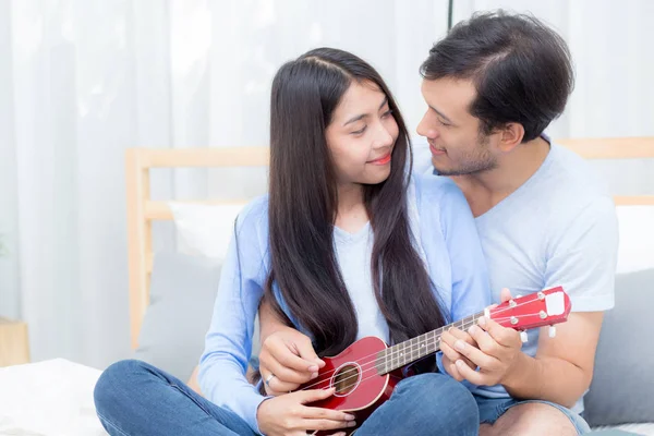 Jovem casal asiático jogar ukulele relaxante com felicidade e j — Fotografia de Stock